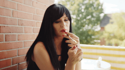 Black haired girl relaxes smokes cigarette looks